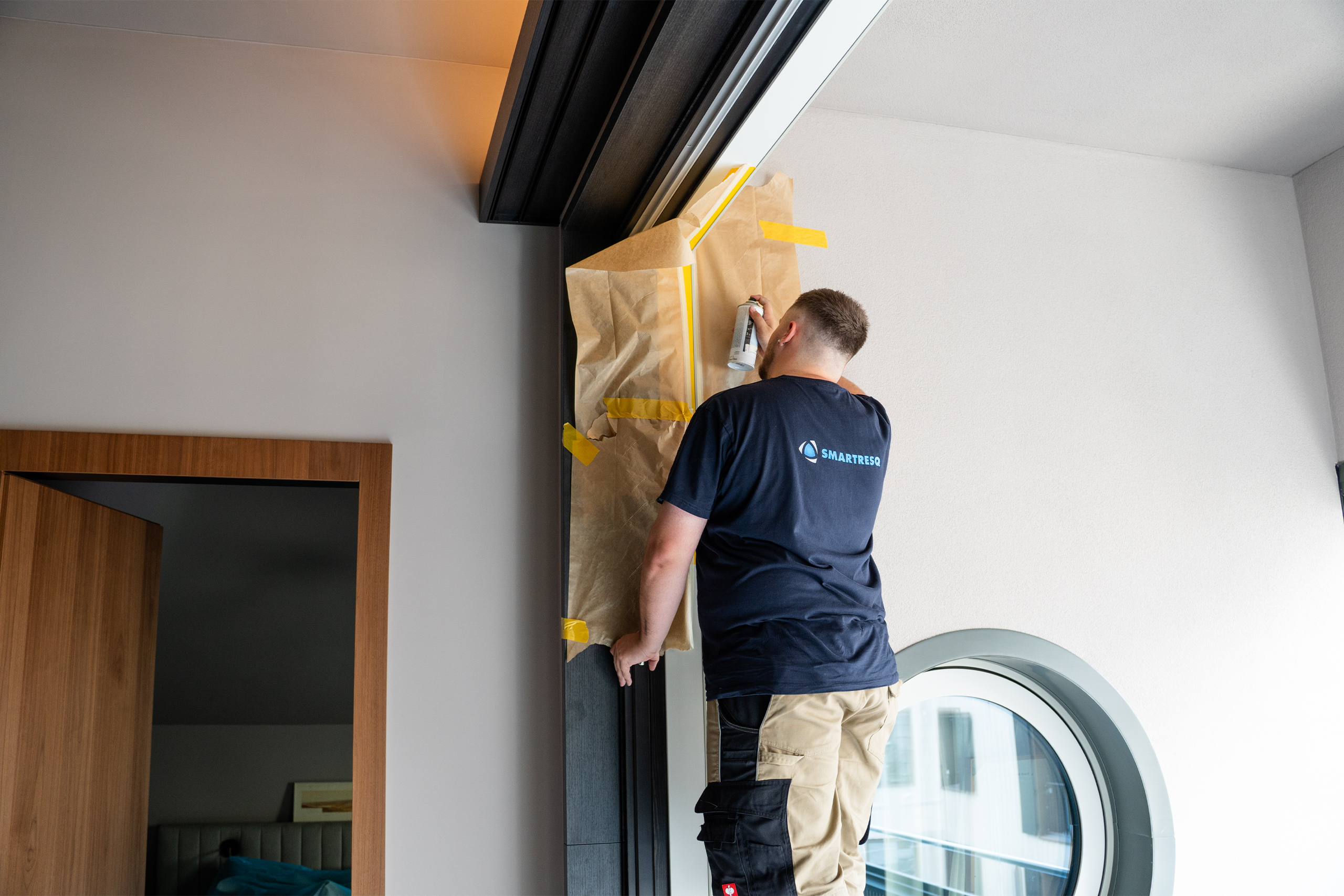 SMARTRESQ Mitarbeiter lackiert Fensterrahmen an der Aussenfassade neu
